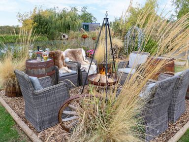 An outdoor seating area with wicker chairs and a fire pit at Bonnie's Shepherds Hut at Shepherds Lodge Retreat and Wellness, Bottesford near Redmile and Vale of Belvoir