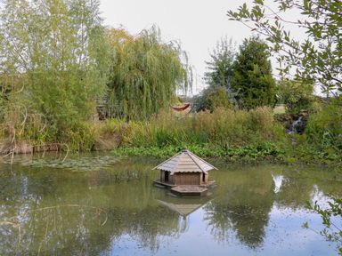 A pond with a shelter and hammock at Bonnie's Shepherds Hut at Shepherds Lodge Retreat and Wellness Bottesford near Redmile and Vale of Belvoir