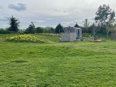 A garden with a shed and flowers at Bonnie's Shepherds Hut at Shepherds Lodge Retreat and Wellness Bottesford near Redmile and Vale of Belvoir