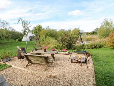 A garden area with a table, chairs, and a fire pit at Lillie's Shepherds Hut at Shepherds Lodge Retreat and Wellness, Bottesford near Redmile and Vale of Belvoir