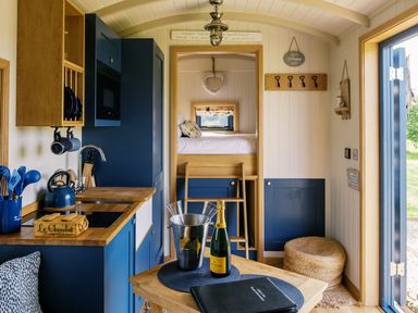 A kitchen with a dining table and champagne at Lillie's Shepherds Hut at Shepherds Lodge Retreat and Wellness Bottesford near Redmile and Vale of Belvoir