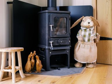 A living room with a wood stove and decorative rabbit at Herbie's Shepherds Hut at Shepherds Lodge Retreat and Wellness Bottesford near Redmile and Vale of Belvoir