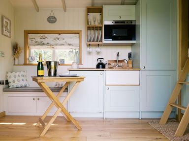 A kitchen with a table and champagne at Herbie's Shepherds Hut at Shepherds Lodge Retreat and Wellness Bottesford near Redmile and Vale of Belvoir