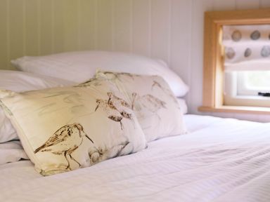 A bed with decorative pillows in a bedroom at Herbie's Shepherds Hut at Shepherds Lodge Retreat and Wellness Bottesford near Redmile and Vale of Belvoir