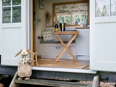 A table with a champagne bottle and bucket in a hut at Herbie's Shepherds Hut at Shepherds Lodge Retreat and Wellness Bottesford near Redmile and Vale of Belvoir