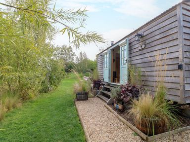 An outdoor view of a shepherd's hut with greenery at Herbie's Shepherds Hut at Shepherds Lodge Retreat and Wellness in Bottesford near Redmile and Vale of Belvoir
