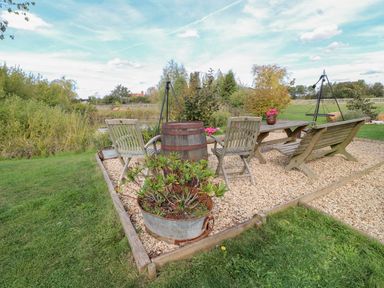 A garden seating area with a table and chairs at Herbie's Shepherds Hut at Shepherds Lodge Retreat and Wellness Bottesford near Redmile and Vale of Belvoir