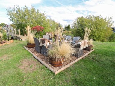 An outdoor seating area with chairs and a table at Herbie's Shepherds Hut at Shepherds Lodge Retreat and Wellness Bottesford near Redmile and Vale of Belvoir