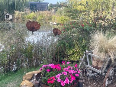 A garden with flowers and decorative metal art at Herbie's Shepherds Hut at Shepherds Lodge Retreat and Wellness, Bottesford near Redmile and Vale of Belvoir