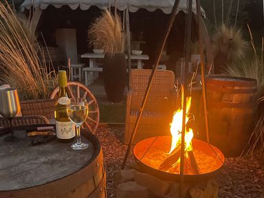 An outdoor area with a fire pit, wine, and chairs at Herbie's Shepherds Hut at Shepherds Lodge Retreat and Wellness, Bottesford near Redmile and Vale of Belvoir