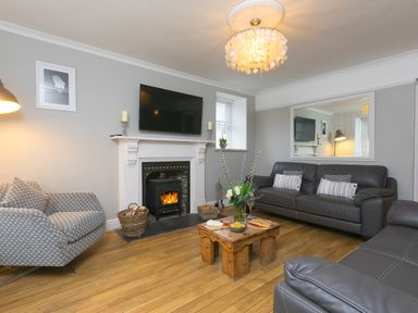 A living room with a fireplace a wooden coffee table and leather sofas at Captain's Walk in Newquay