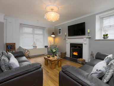 A living room with two leather sofas a wooden coffee table fireplace and a television at Captains Walk in Newquay