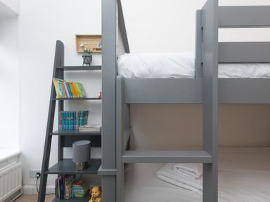 A grey bunk bed next to a grey shelving unit with books and a lamp at Captains Walk in Newquay