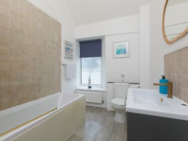 A bathroom with a bathtub a toilet a sink and a window at Captains Walk in Newquay