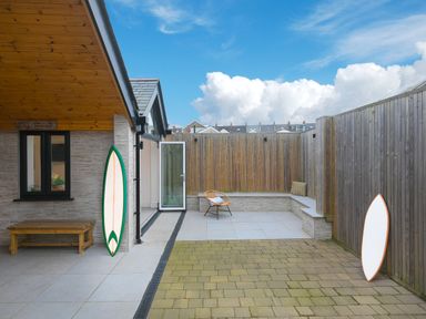 A backyard patio with a bench chair and two surfboards at Captains Walk in Newquay