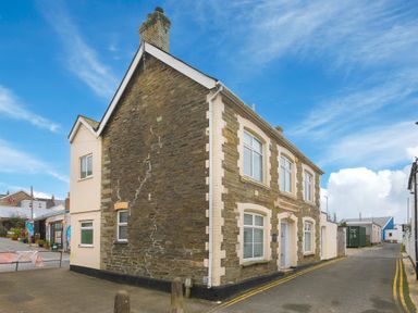A stone building with white framed windows on a street corner at Captains Walk in Newquay