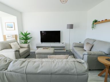 A living room with gray sofas a flat screen tv a floor lamp and a plant at 6 Gwel Yr Wyddfa in Llanfaelog near Rhosneigr