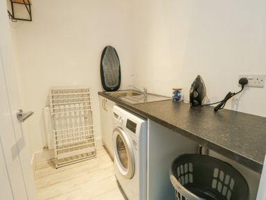A laundry room with a washing machine a countertop sink an iron and a drying rack at 6 Gwel Yr Wyddfa Llanfaelog near Rhosneigr