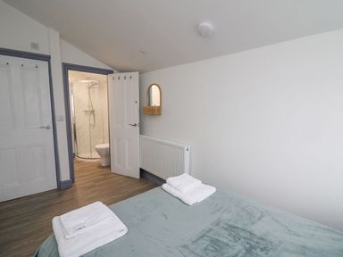 A bedroom with a bed covered with towels and a view towards a bathroom with a shower at Fronwig in New Quay