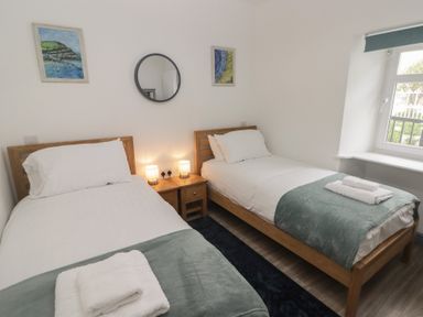 A bedroom with two single beds with white bedding and green throws at Fronwig in New Quay