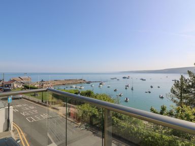 A view of a harbor with boats in the water and a road in the foreground at Fronwig in New Quay