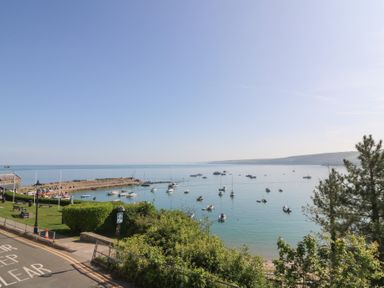 A coastal view with boats on water and a small harbor with benches and a road at Fronwig in New Quay
