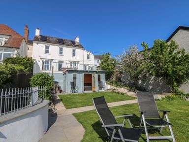A backyard with lawn chairs and a shed in front of a white house at Fronwig in New Quay