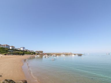 A beach with boats in the water and houses on the shore at Fronwig in New Quay