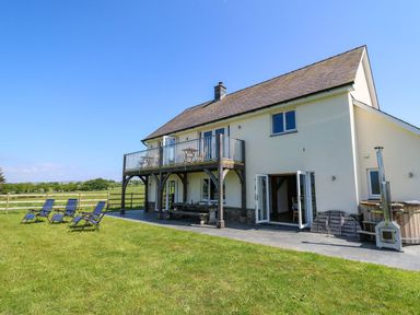 A house with a wooden balcony and patio chairs on a lawn at Yr Adfa Llangeitho near Tregaron