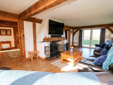 A living room with wooden beams a fireplace a coffee table and leather sofas at Yr Adfa in Llangeitho near Tregaron