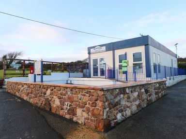 A reception office building with stone walls and blue railings at Newpark Holiday Park
