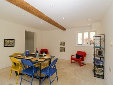 A dining room with a table set for six and colorful chairs at Home Farm Barn Todenham near Moreton-In-Marsh