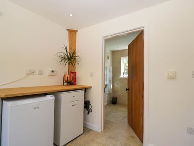 A small utility area with two white appliances under a wooden countertop and a plant on top at Home Farm Barn Todenham near Moreton-In-Marsh