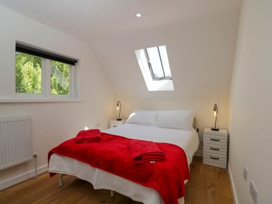 A bedroom with a double bed and bedside tables under a skylight window at Home Farm Barn in Todenham near Moreton-In-Marsh