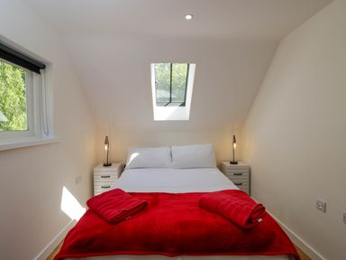 A bedroom with a double bed bedside tables and lamps under a skylight window at Home Farm Barn in Todenham near Moreton-In-Marsh