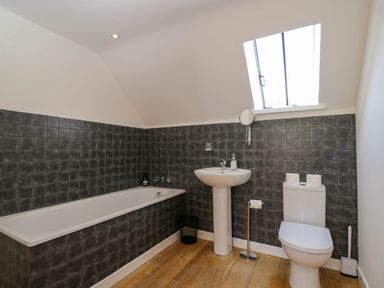 A bathroom with a bathtub a pedestal sink a toilet and a skylight window at Home Farm Barn in Todenham near Moreton-In-Marsh