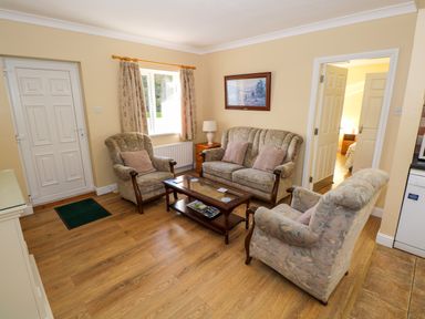 A living room with a sofa set and coffee table near a window and doors at Robins Roost 2 in Cornamona County Galway