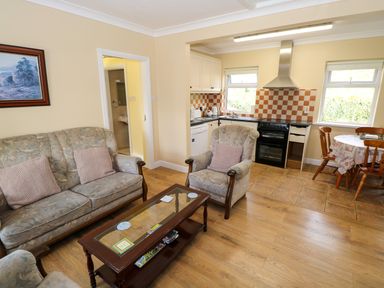 A combined living room and kitchen with sofas a coffee table a stove and a dining table at Robin's Roost 2 in Cornamona County Galway