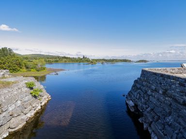 A body of water with stone walls on both sides and trees in the background at Robin's Roost 2 in Cornamona County Galway