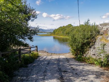 A dirt path leading to a lake surrounded by trees and hills at Robin's Roost 2 in Cornamona County Galway