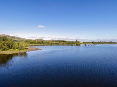 A body of water with a shoreline and hills in the background at Robin's Roost 2 in Cornamona County Galway