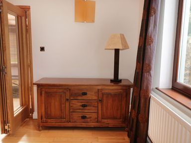 A wooden sideboard with a table lamp next to a window in a room at Walworth Castle Lodge in Walworth near Darlington