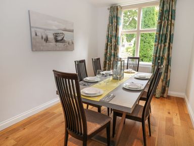 A dining room with a table set for six by a window with patterned curtains at Walworth Castle Lodge in Walworth near Darlington