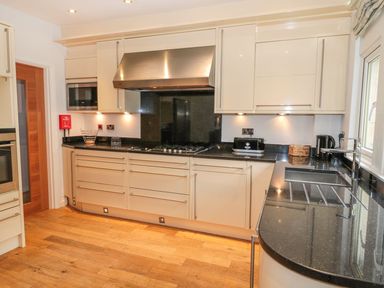 A kitchen with black countertops cream cabinets gas stove and sink at Walworth Castle Lodge in Walworth near Darlington