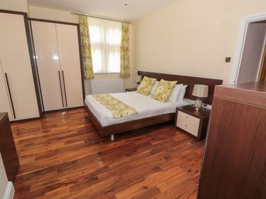A bedroom with a double bed yellow floral cushions curtains wooden wardrobes and bedside tables at Walworth Castle Lodge in Walworth near Darlington