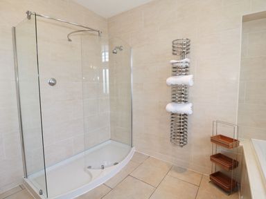 A bathroom with a walk-in shower and towel rack with towels at Walworth Castle Lodge in Walworth near Darlington