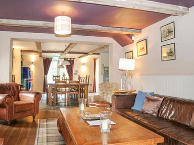 A living room with leather armchairs a wooden coffee table and a dining area with a wooden table and chairs at Moles Cottage Farnham near Sixpenny Handley