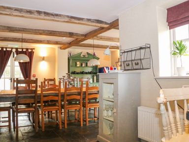 A dining room with a wooden table and chairs a green cabinet and a window at Moles Cottage Farnham near Sixpenny Handley