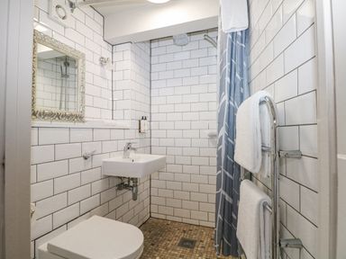 A bathroom with a toilet sink shower area with curtain and towel rack at Moles Cottage in Farnham near Sixpenny Handley
