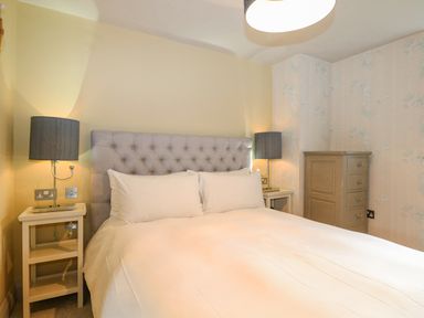 A bedroom with a bed with a tufted headboard two bedside tables with lamps and a chest of drawers at Moles Cottage in Farnham near Sixpenny Handley